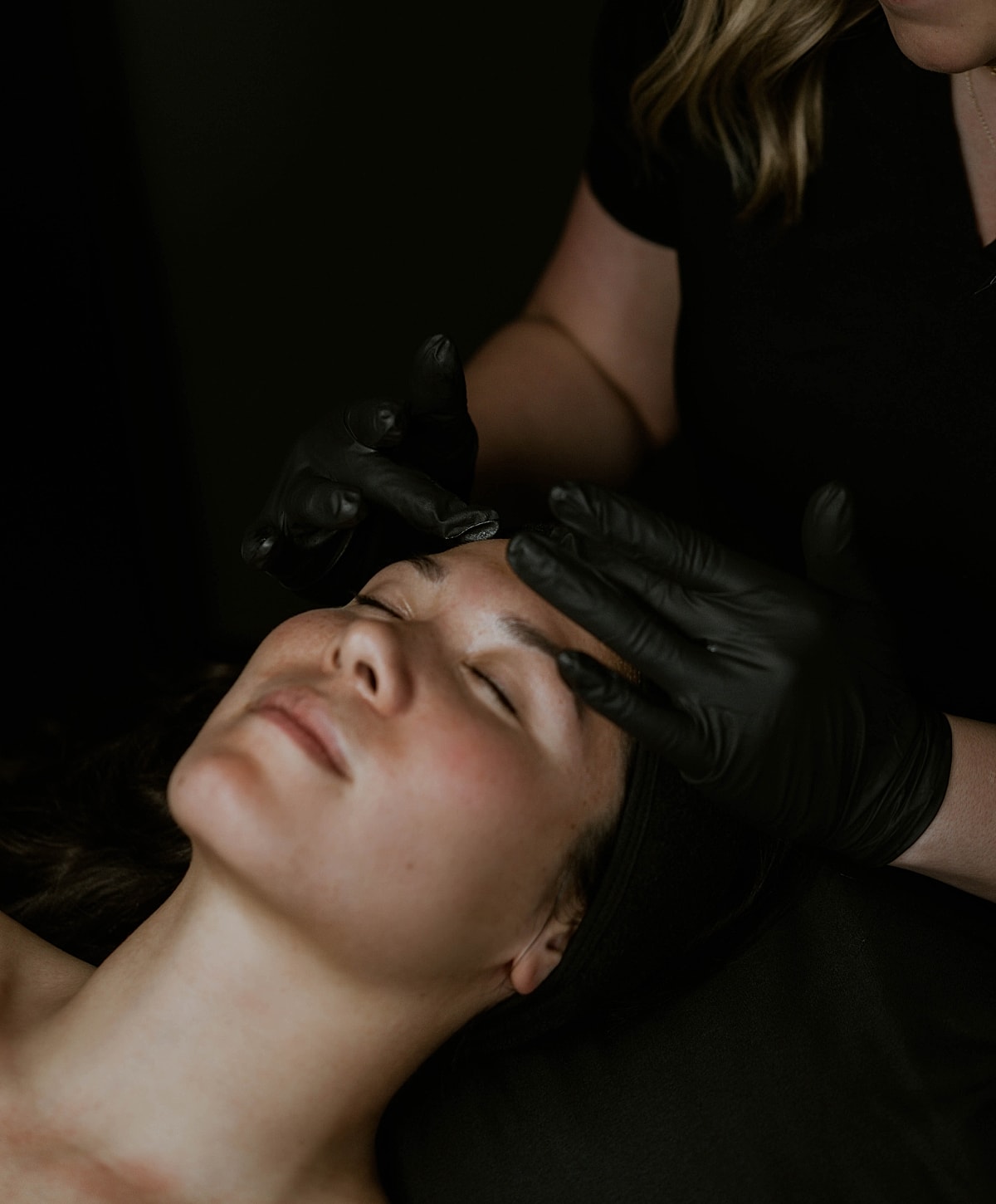 Applying makeup on a woman's eyebrows.