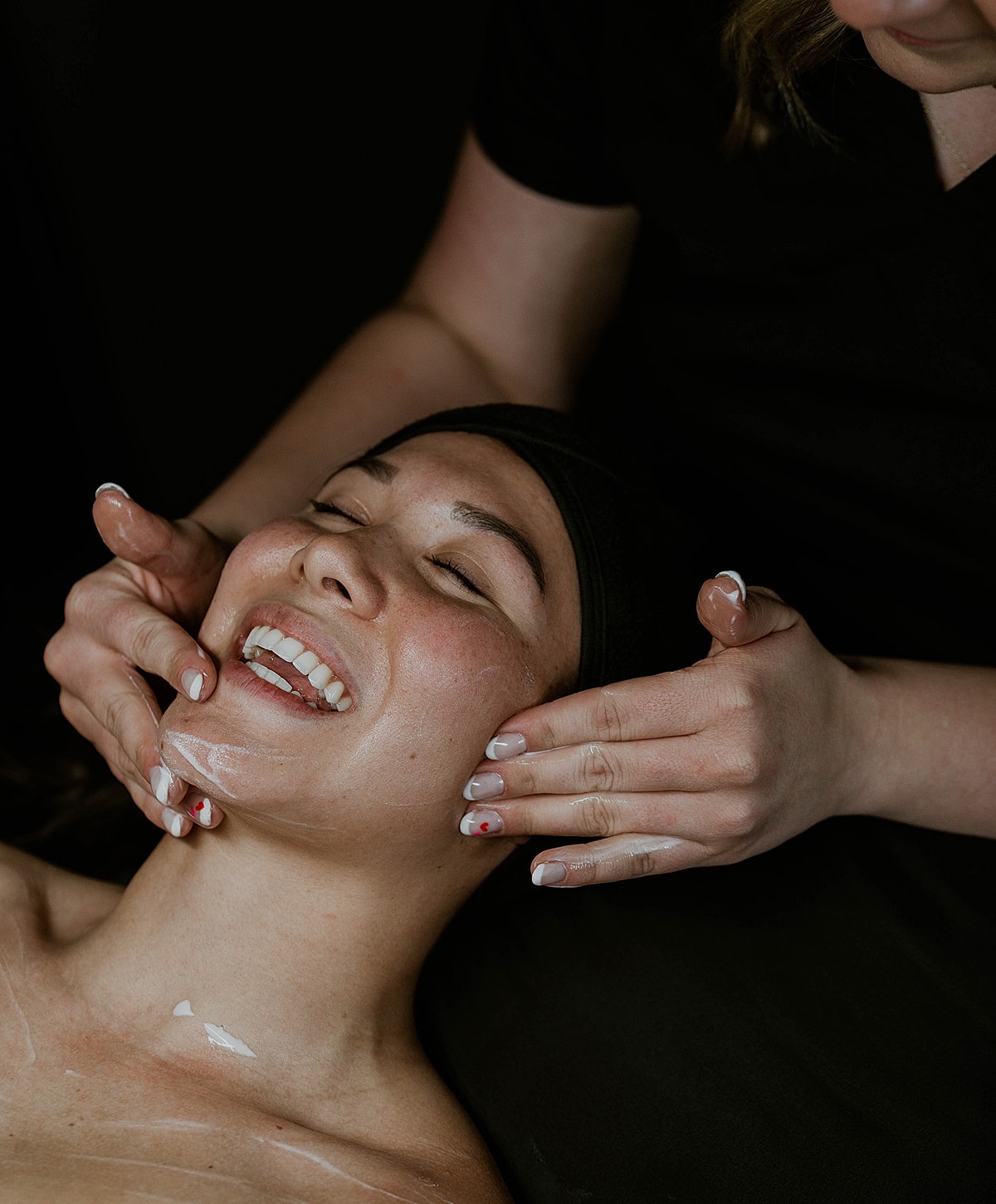 Facial treatment with smiling client and aesthetician.