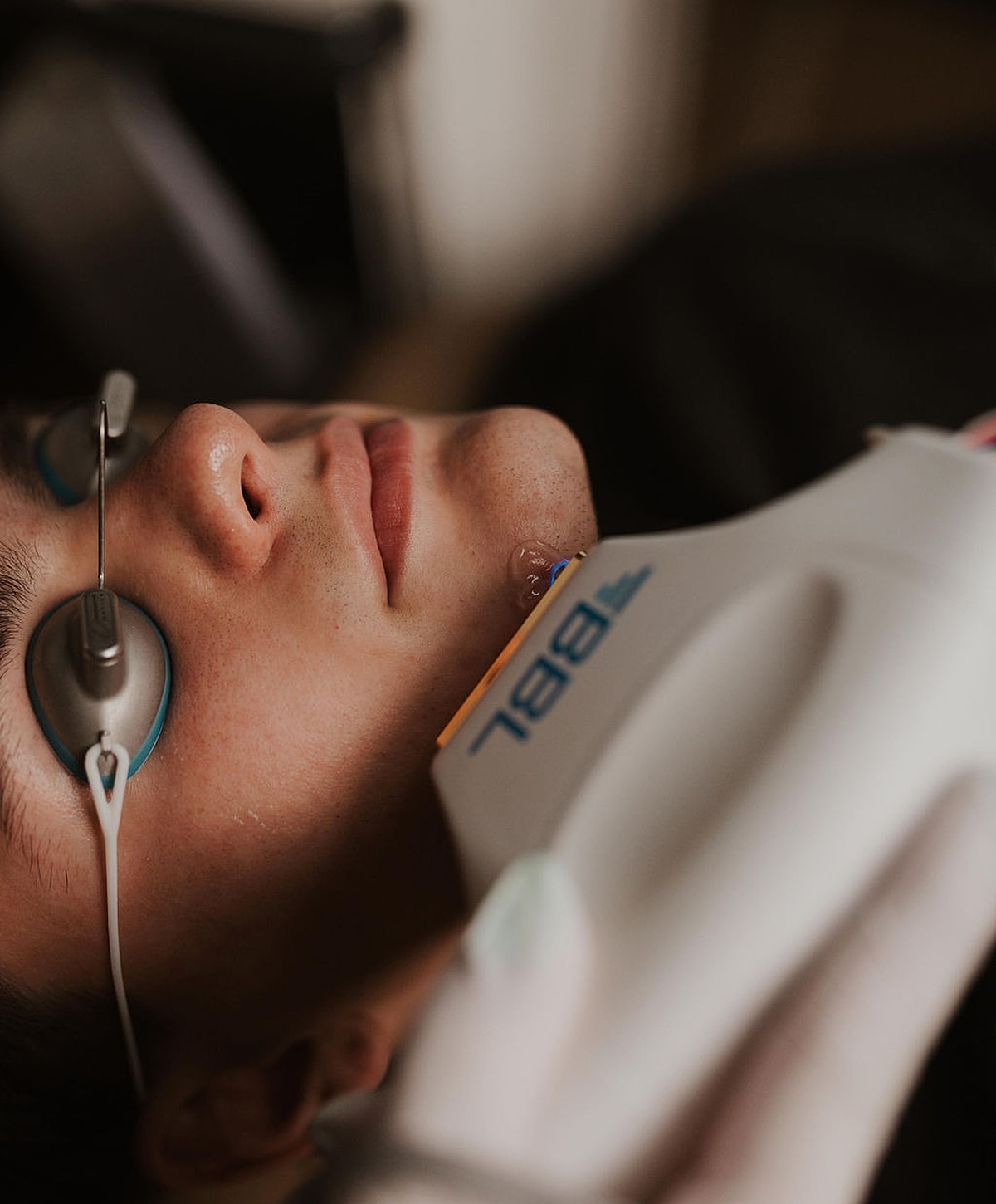 Person receiving a facial treatment with devices.