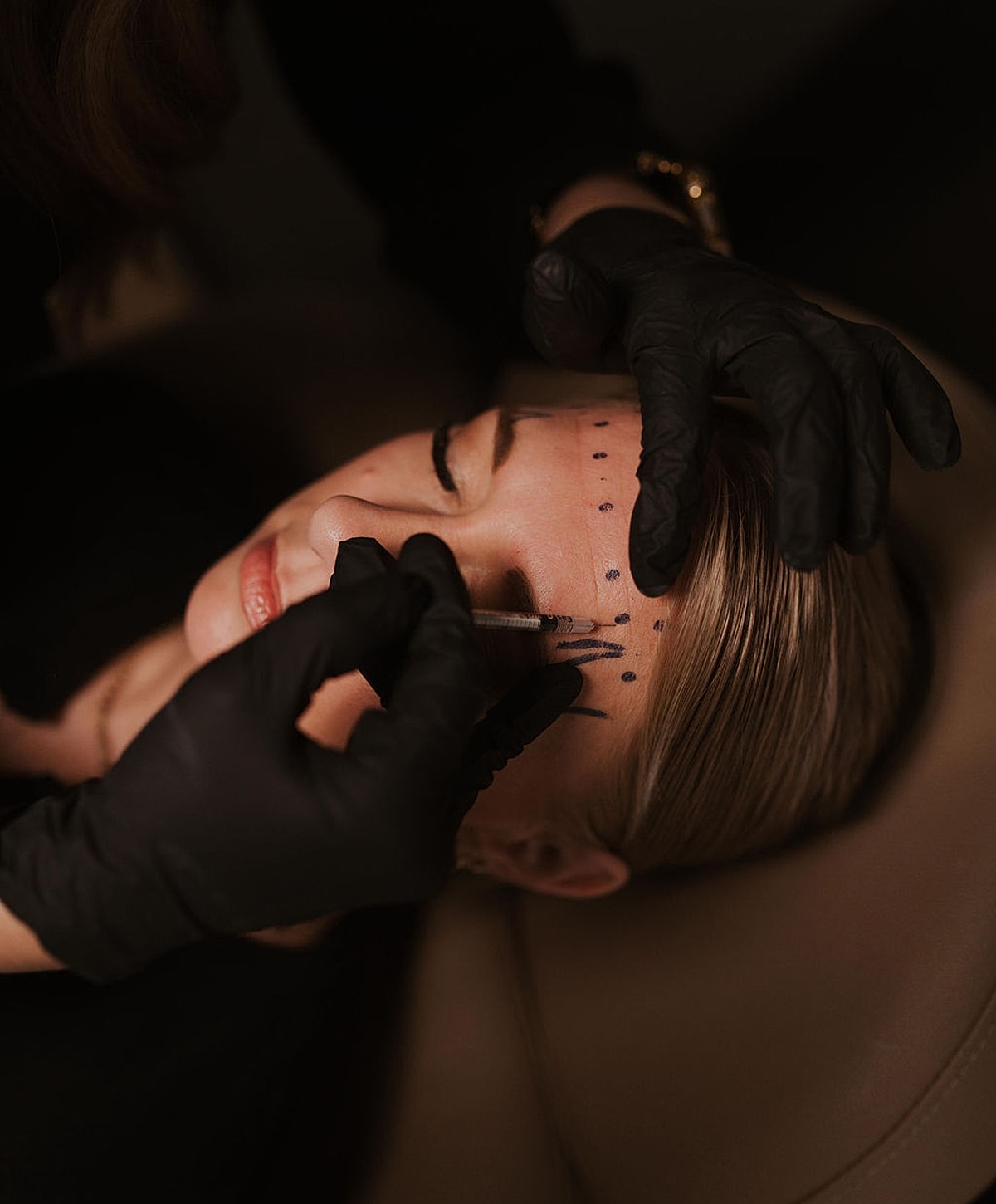 Woman receiving eyebrow tattooing procedure.