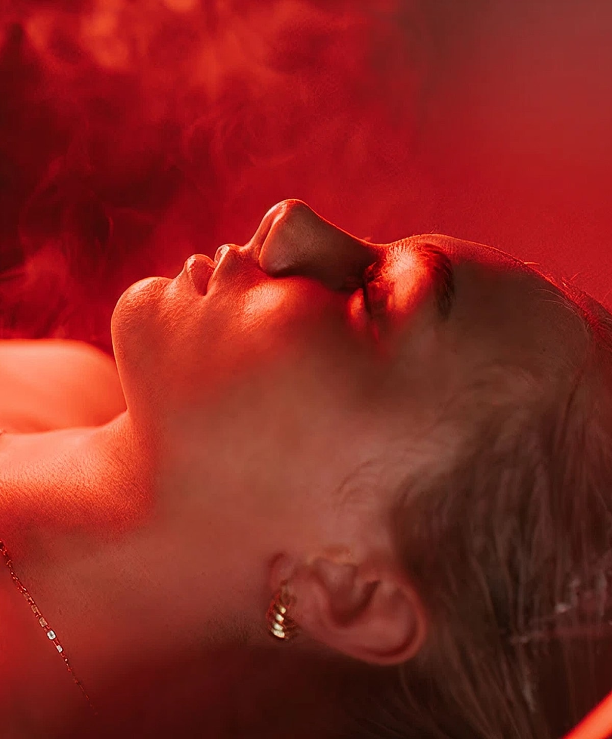 Person relaxing with red lighting and smoke.