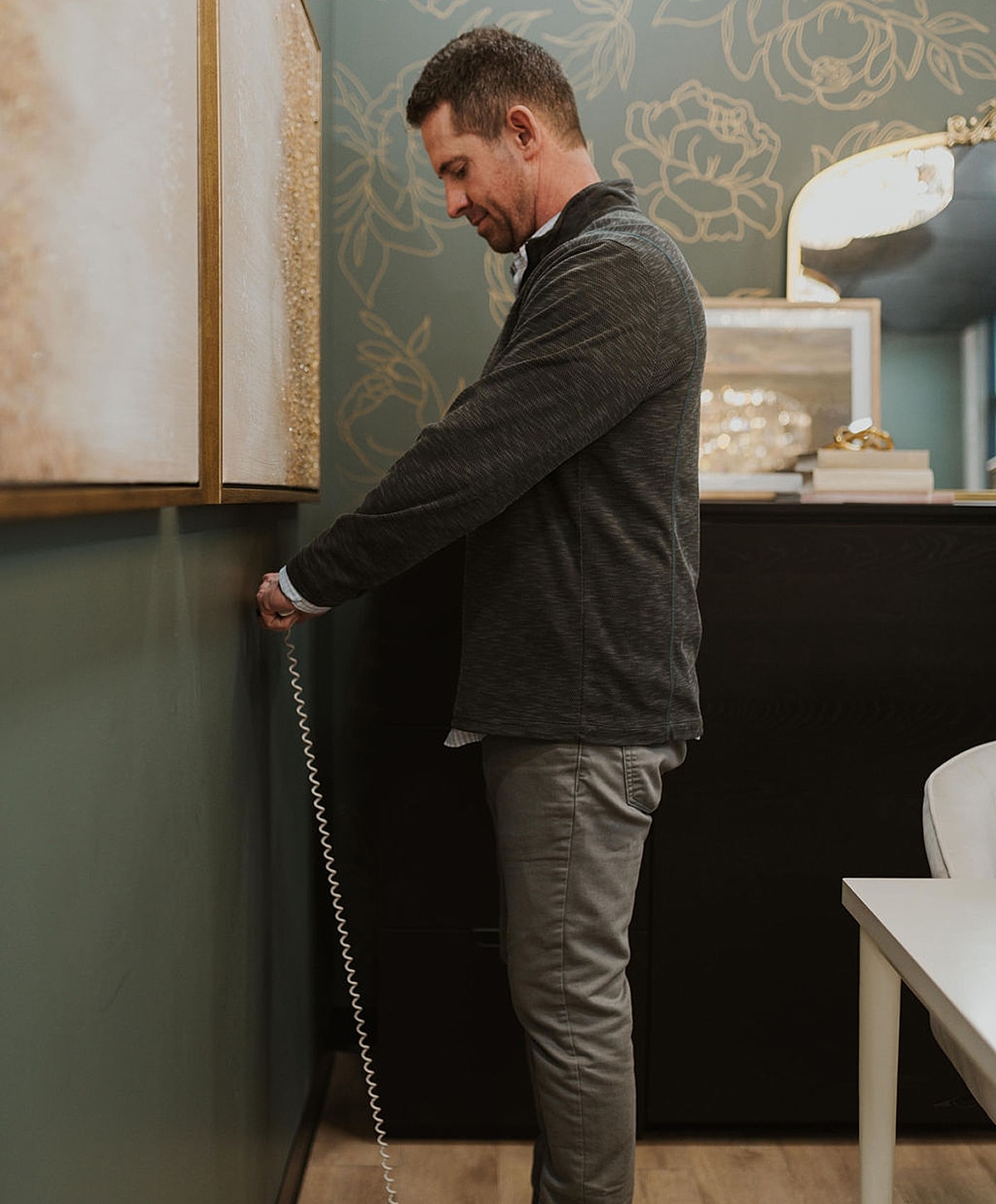 Man reaching for phone cord in office.