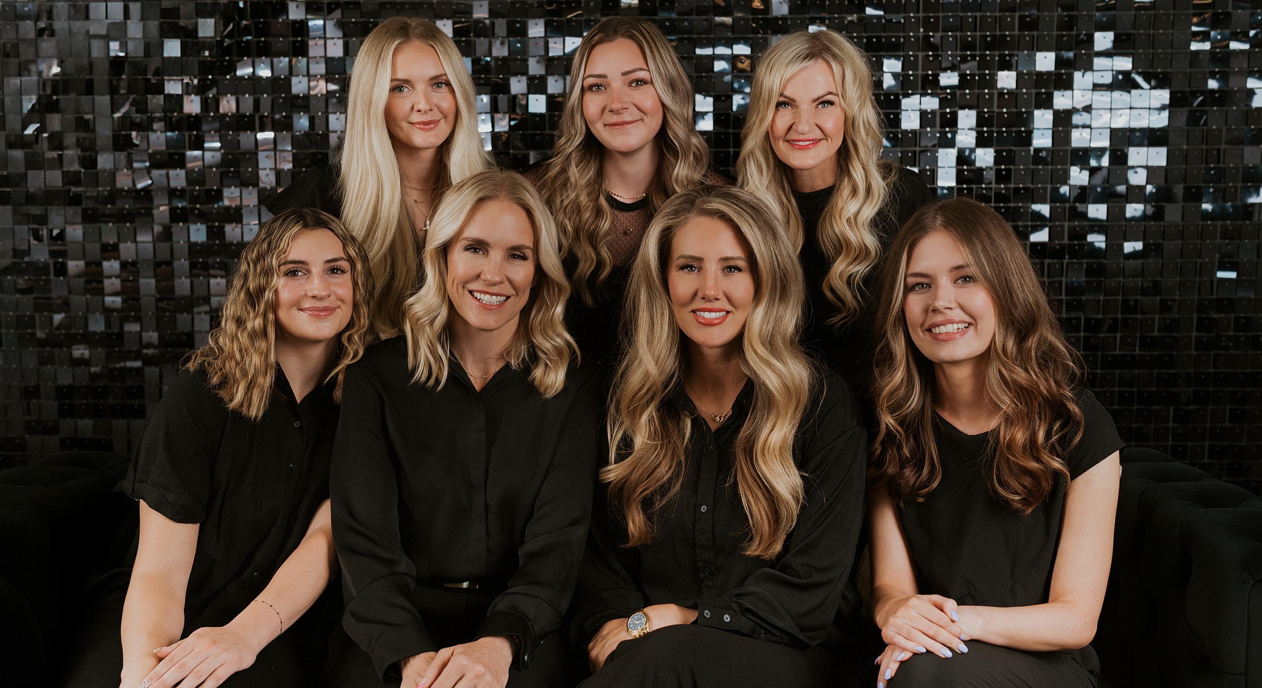 Group of women smiling together in black outfits.