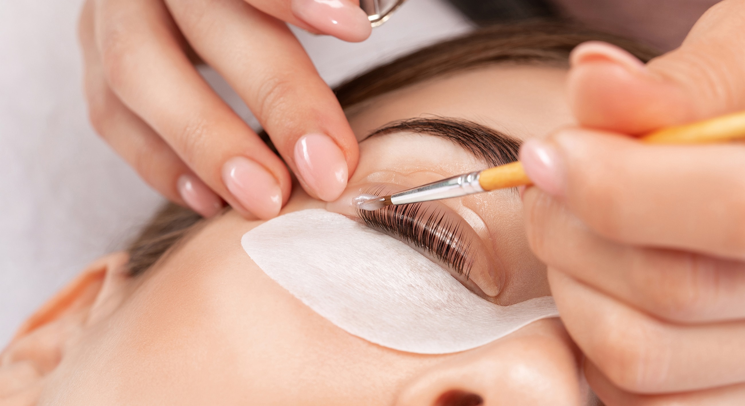 Applying eyelash extension treatment on a client.